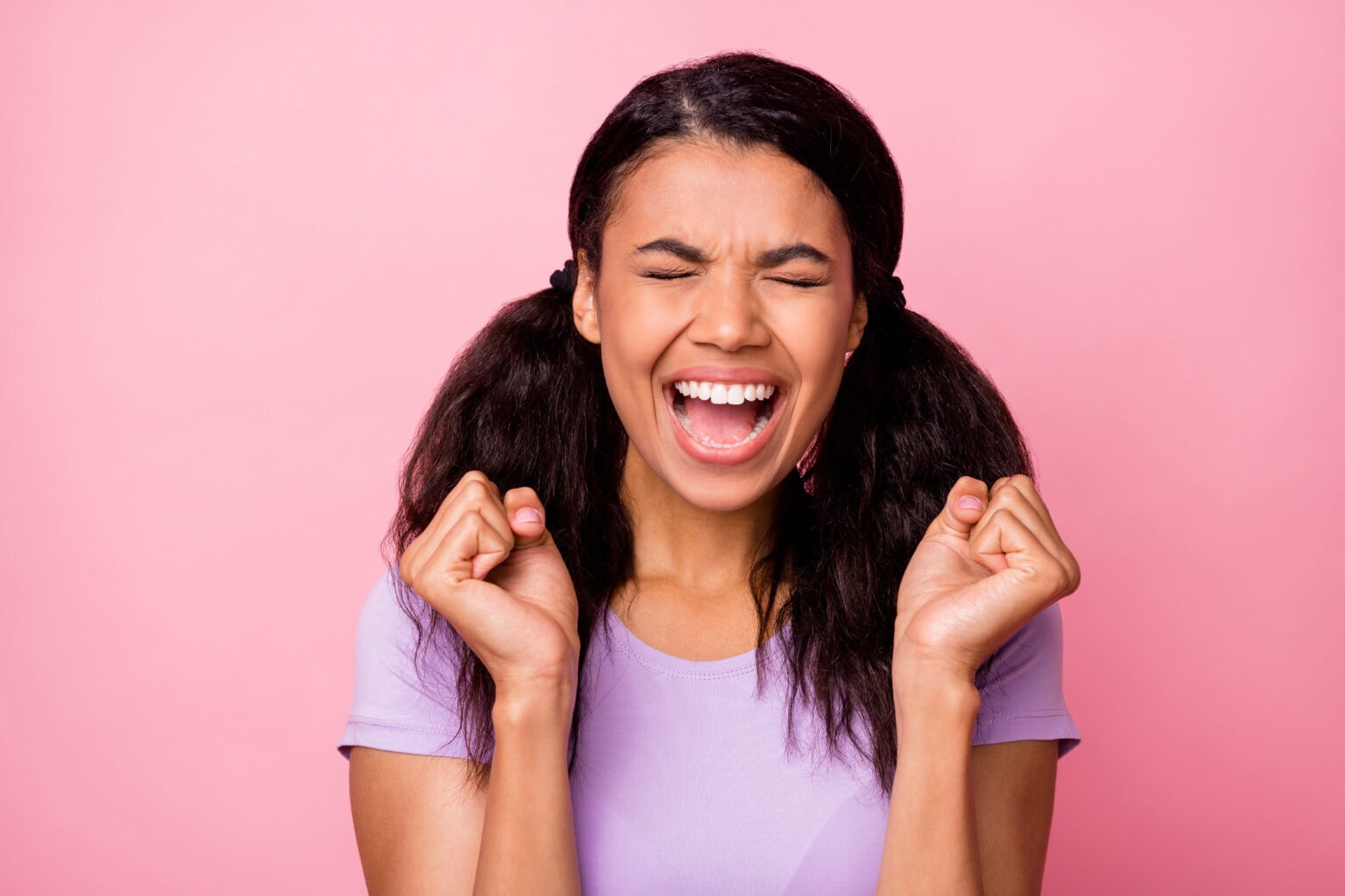 Smiling woman celebrating against a pink background