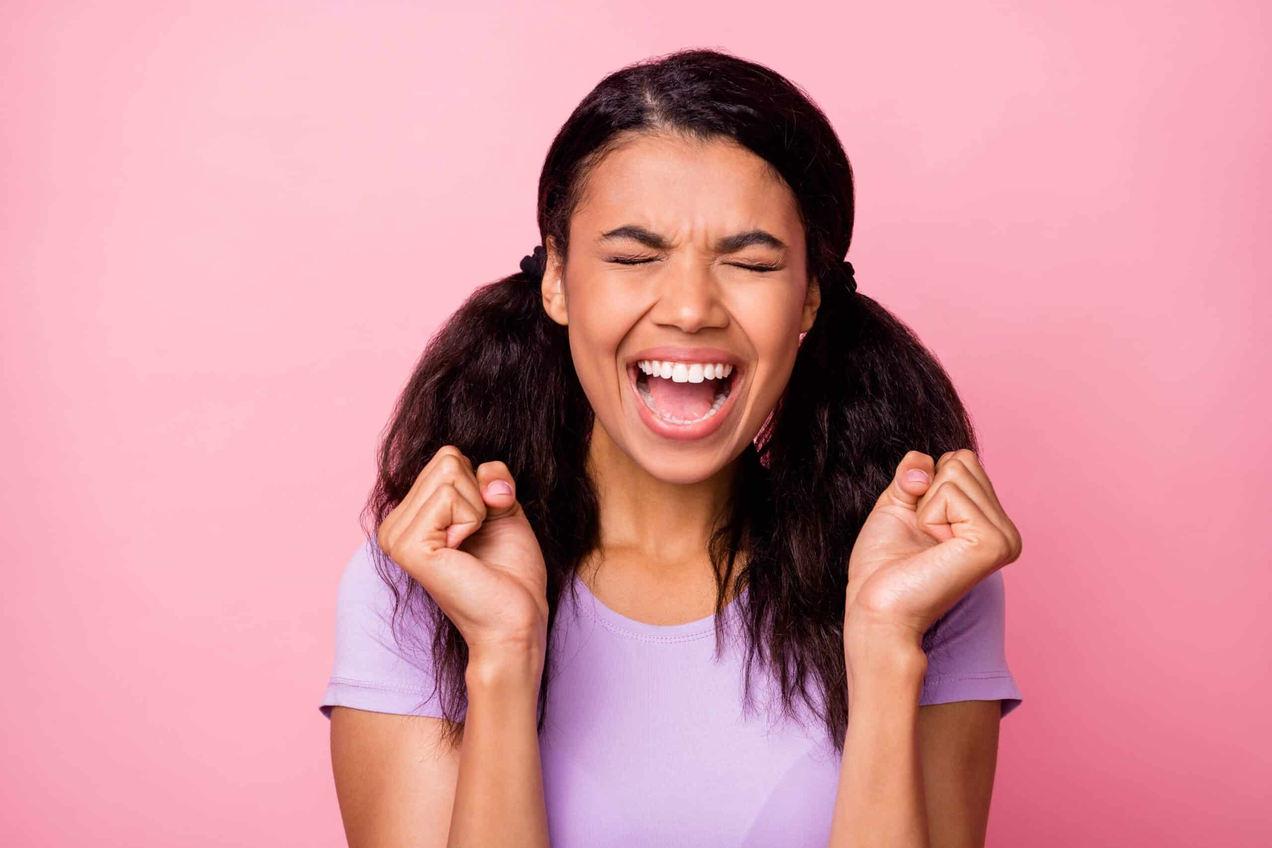 Excited young woman celebrating her new straight smile after Invisalign orthodontic treatment at Empower Orthodontics.